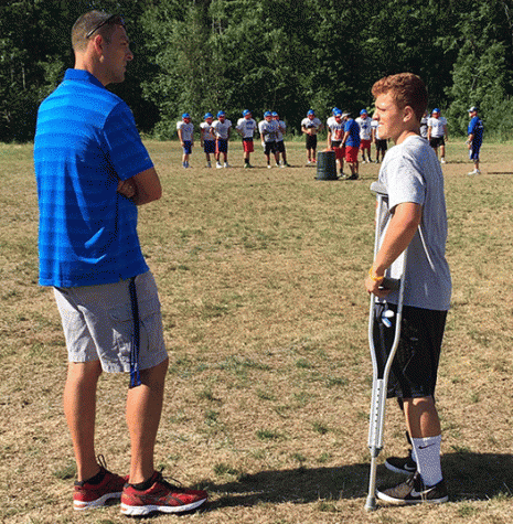 Secor, a football fan, speaks with senior Brandon Proulx at football practice. 