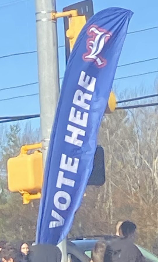 A sign is set up to remind residents that voting takes place in the LHS gym. Polls open at 6 am and close at 8 pm on Nov. 8. Major focus is on Donald Bolduc, Karoline Leavitt, Chris Pappas, and Maggie Hassan.